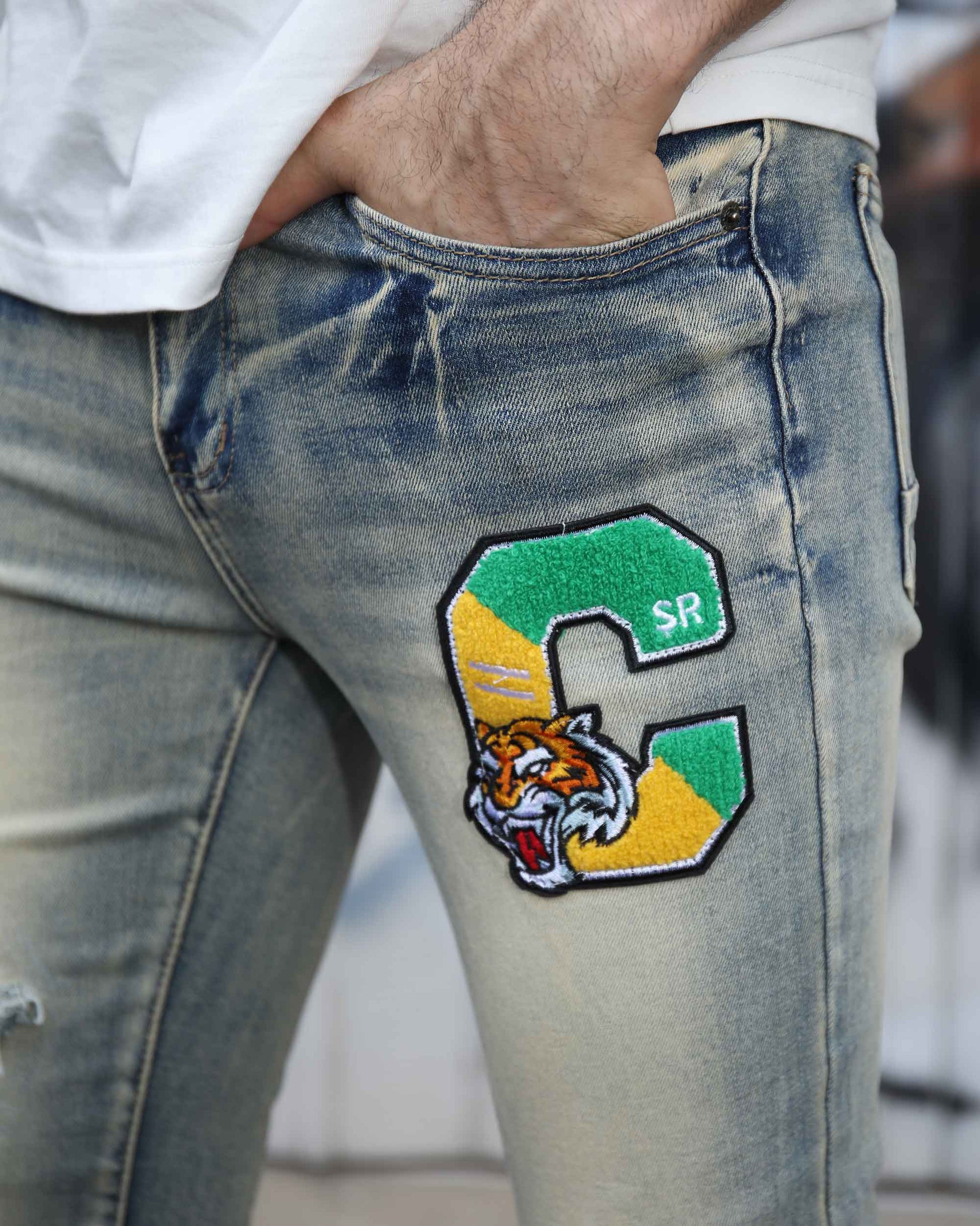 Logeqi distressed light wash jeans with a green and yellow tiger patch on thigh