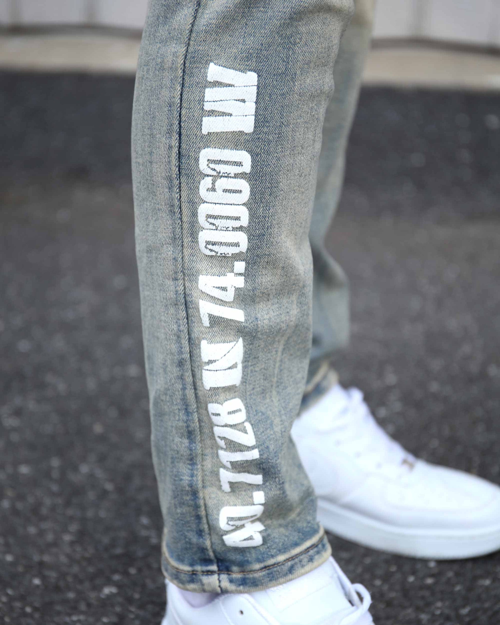 Logeqi distressed light wash jeans with white graphic text on the leg paired with white sneakers