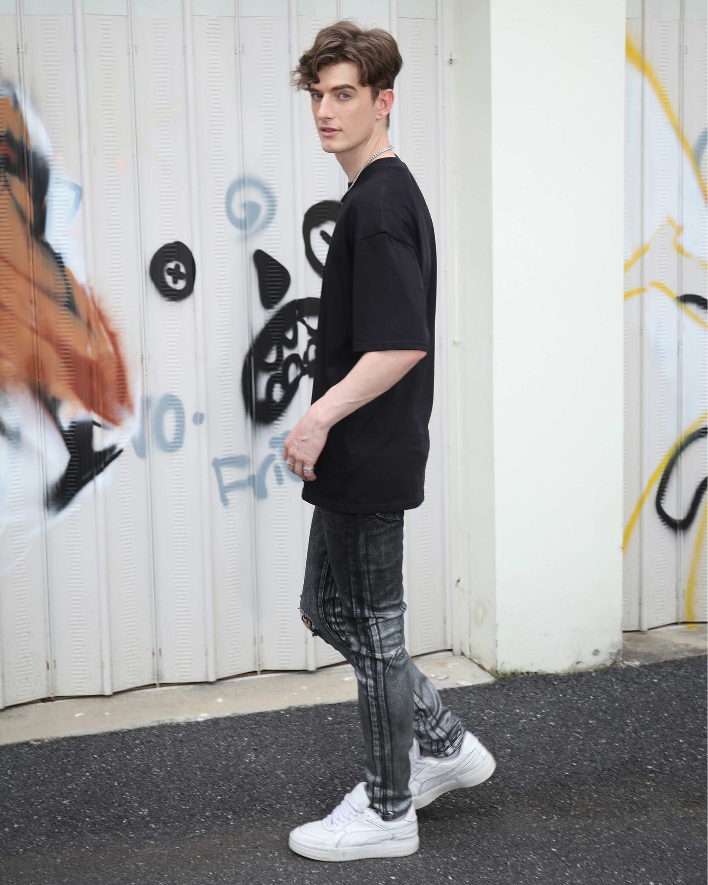 Logeqi gradient ripped black jeans worn by a male model with white sneakers and black t-shirt