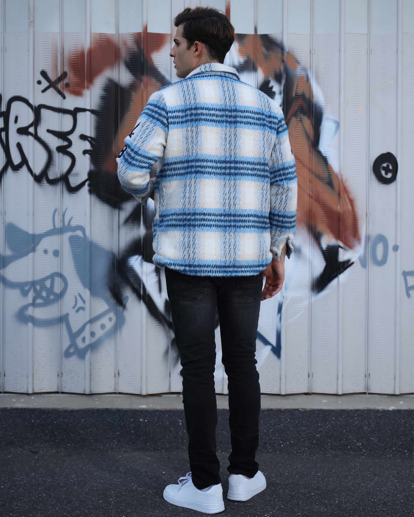 Logeqi insulated plaid moto jacket in blue and white worn by a man standing in front of graffiti wall