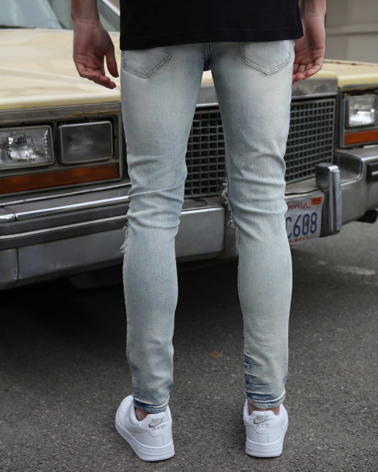Logeqi light wash graffiti jeans worn by man standing in front of vintage car on street