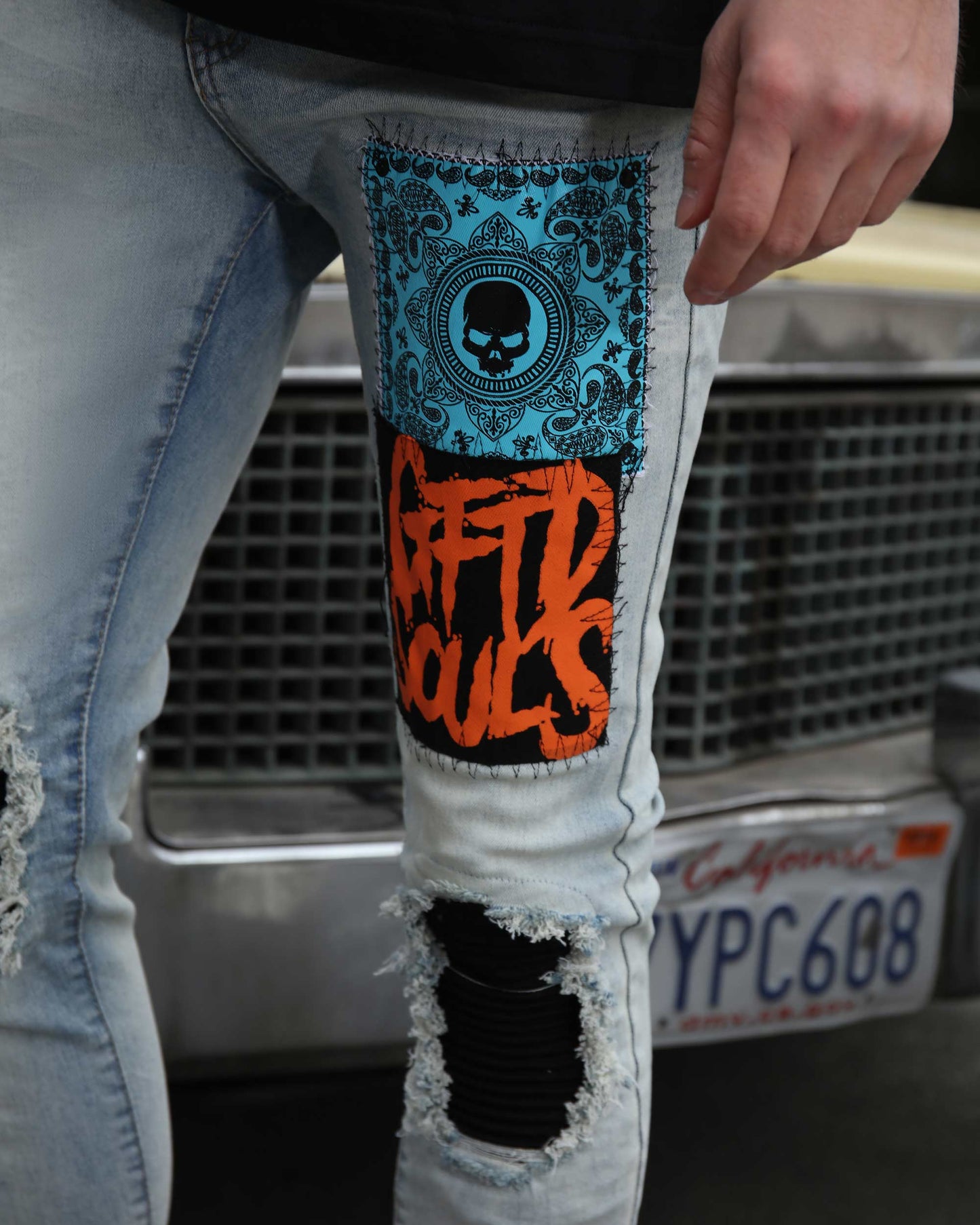 Logeqi light wash graffiti jeans with blue skull and orange graphic patches and distressed detailing