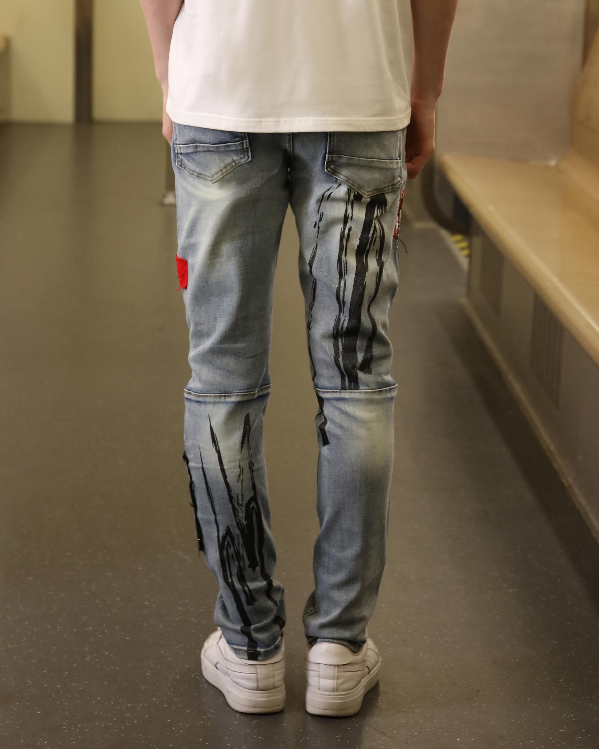 Logeqi medium wash ripped jeans with black paint splatter design on back and red patch detail