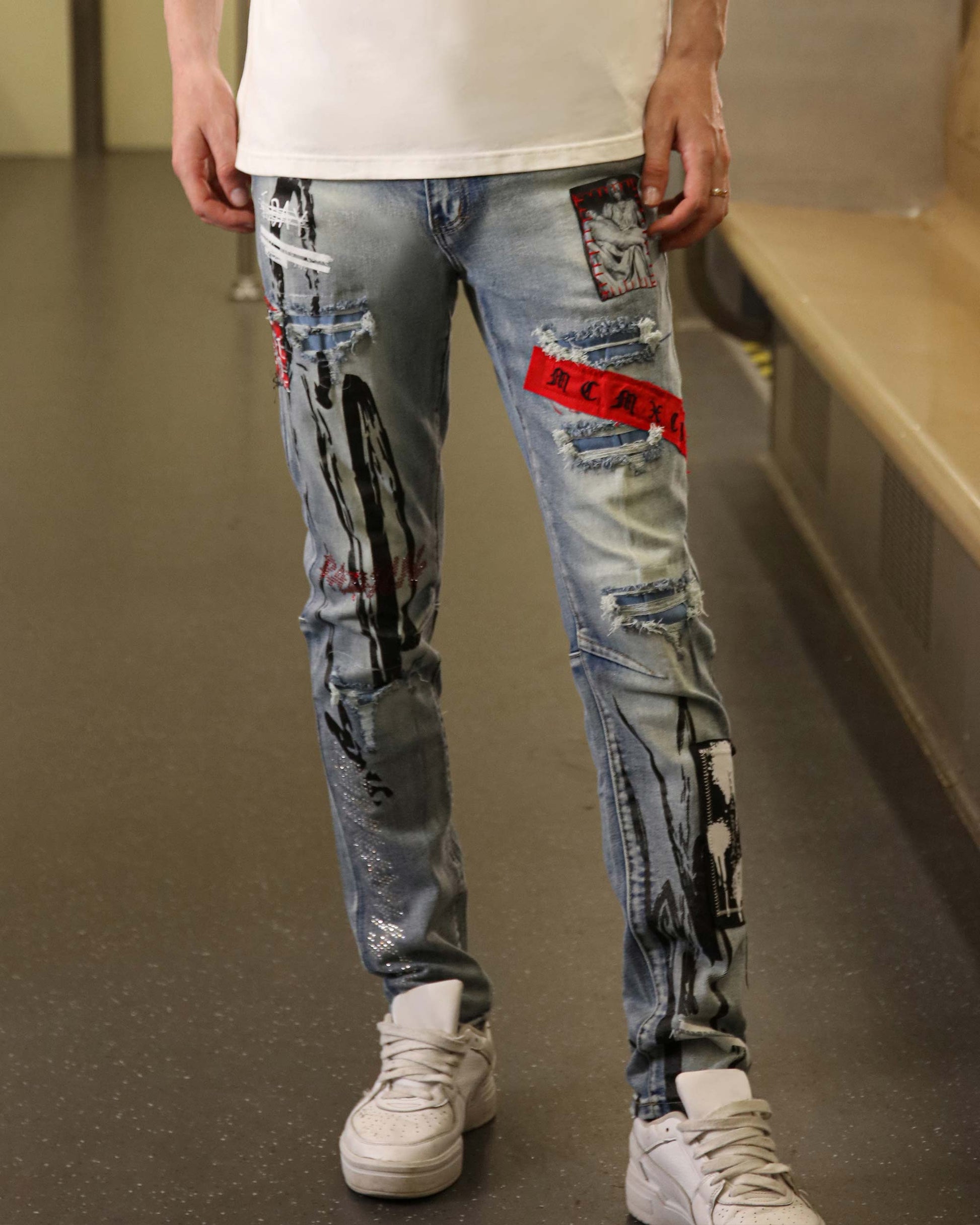 Logeqi medium wash ripped jeans with graphic patches and distressed detailing on legs