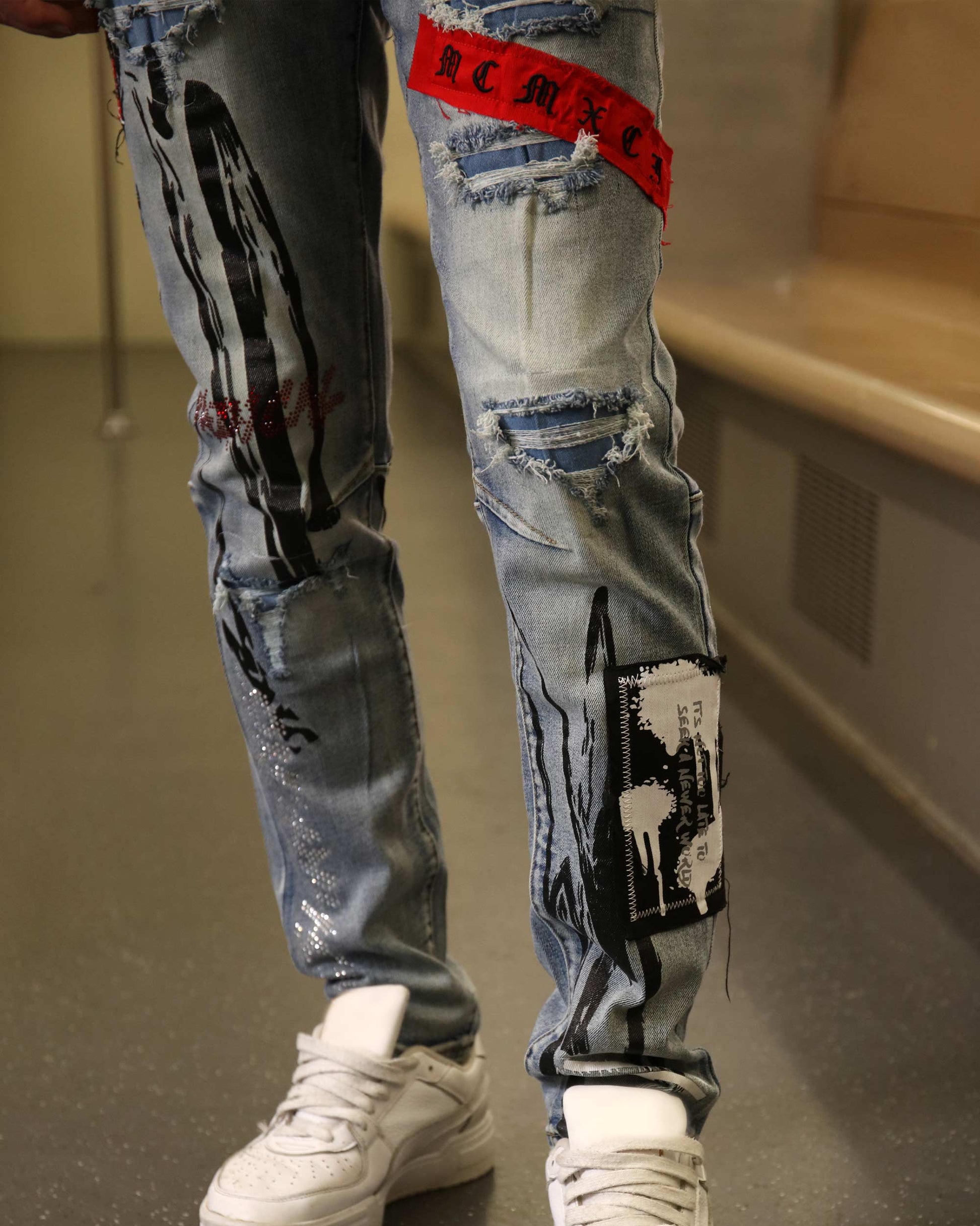 Logeqi medium wash ripped jeans with distressed patches and graphic details on front legs