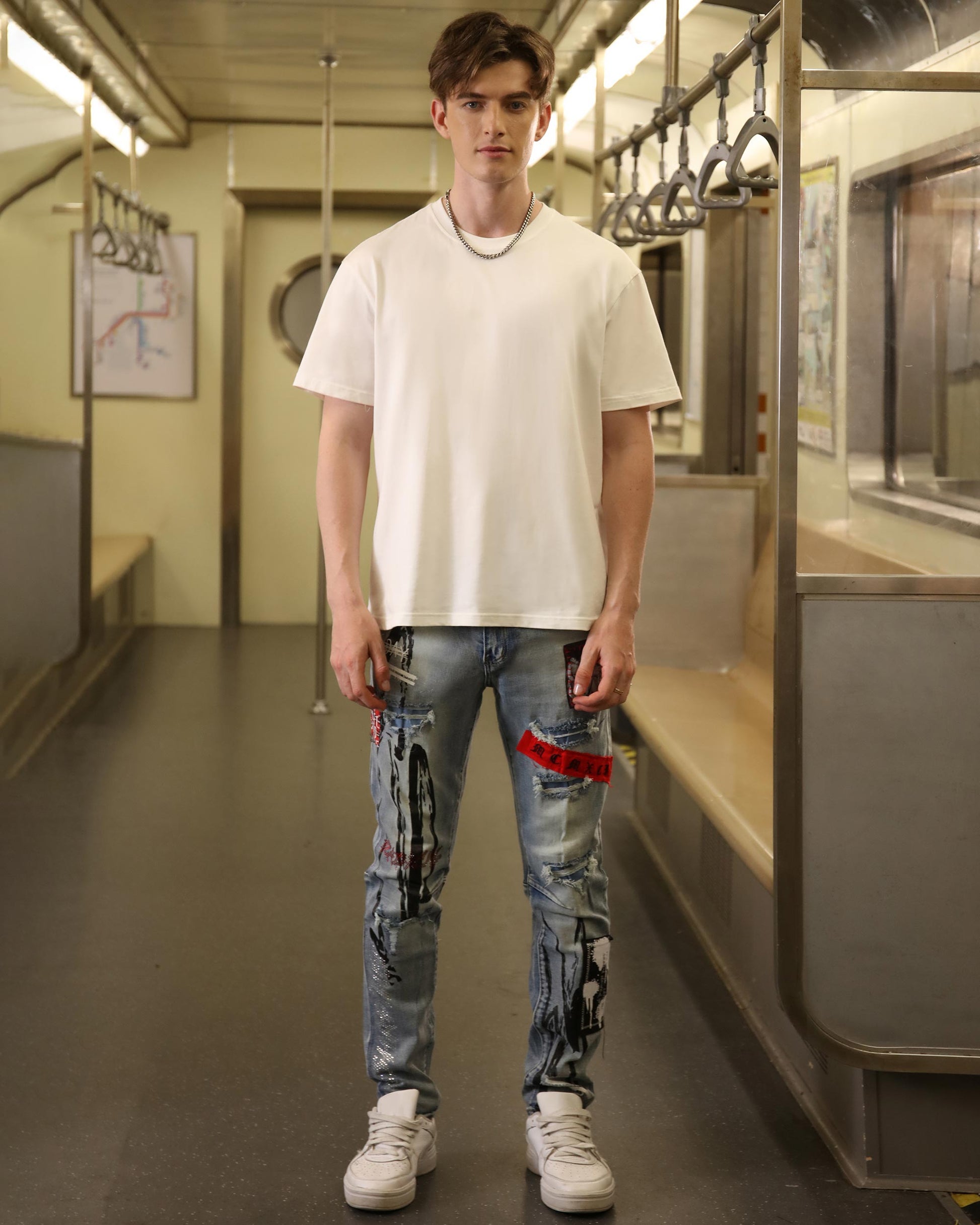 Logeqi medium wash ripped jeans with artistic paint splatter worn by male model in white t-shirt