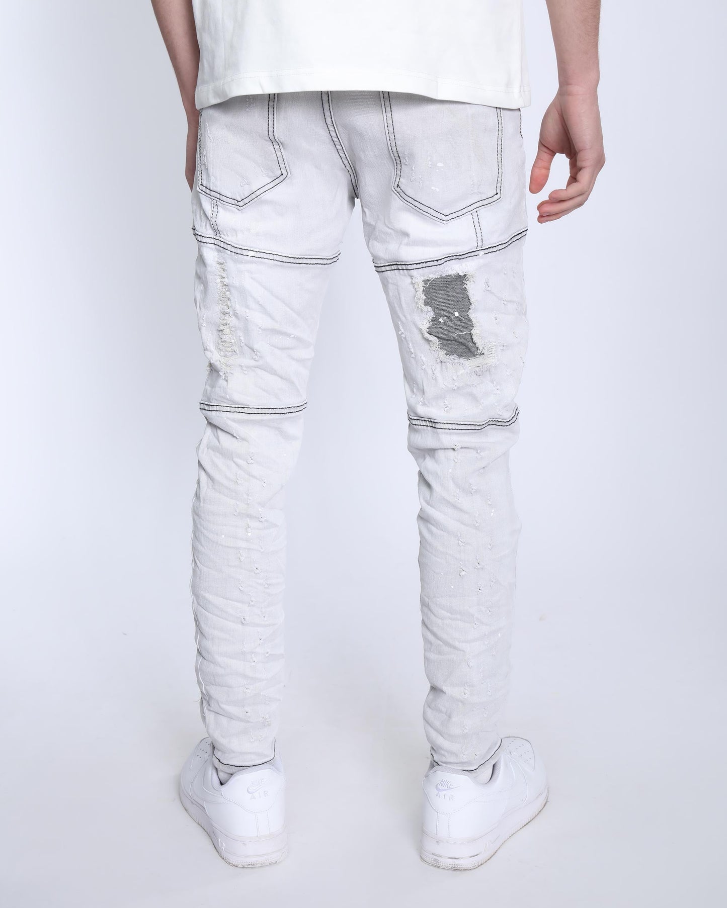 Back view of slim fit gray distressed jeans by Logeqi worn with white sneakers and a white shirt