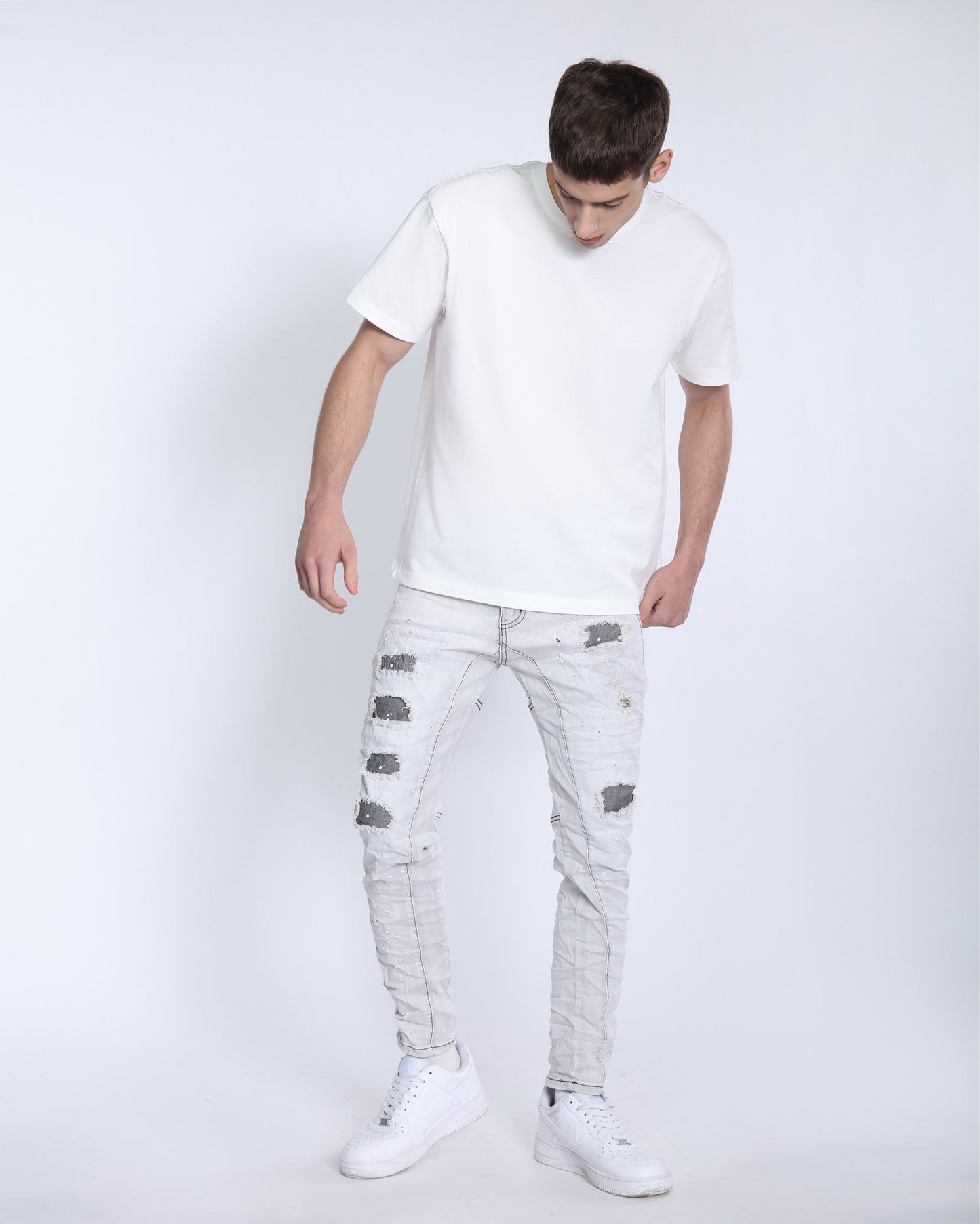 Man wearing Logeqi slim fit gray distressed jeans paired with a white t-shirt and white sneakers