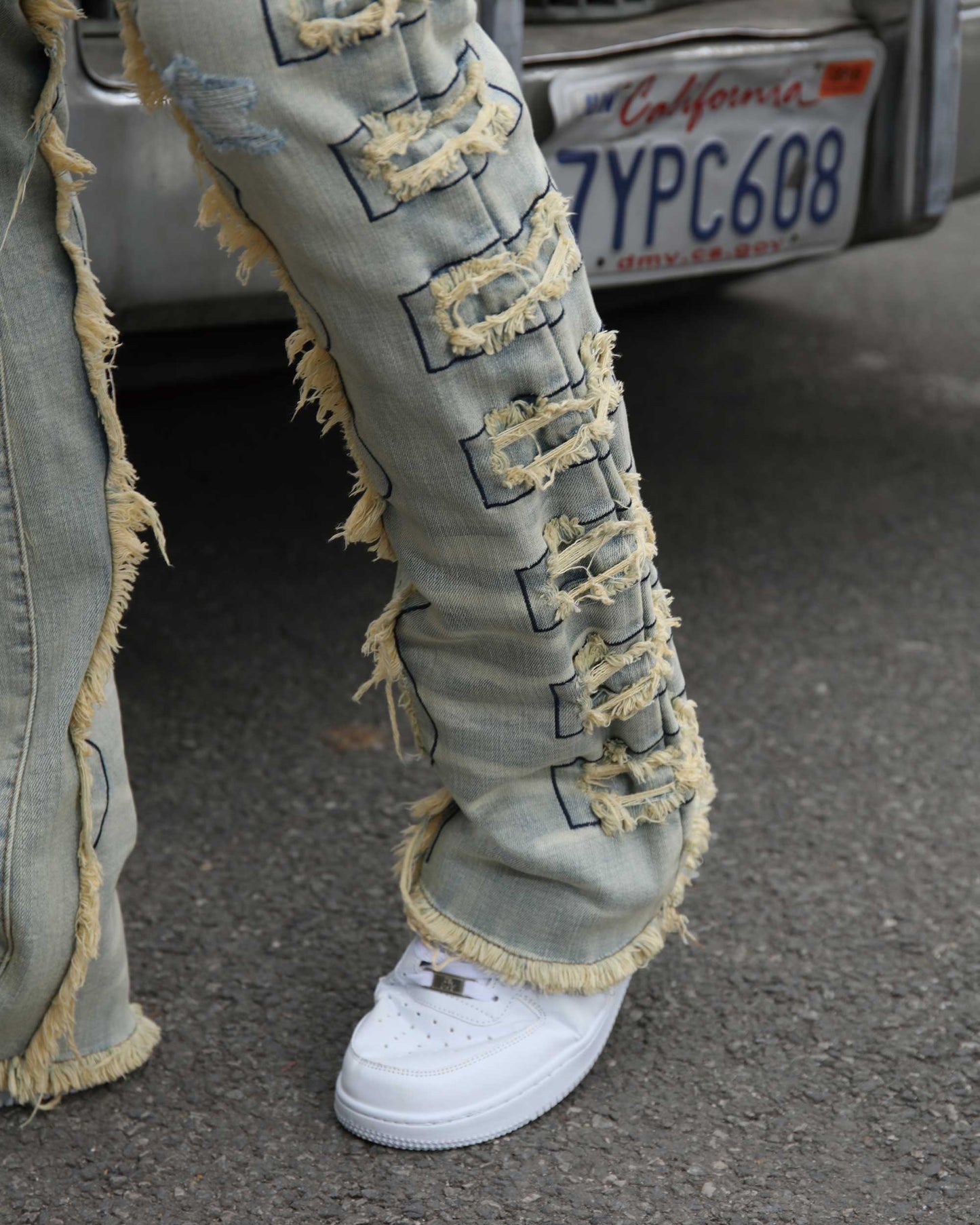 Logeqi vintage blue stacked jeans with distressed patches and frayed edges paired with white sneakers