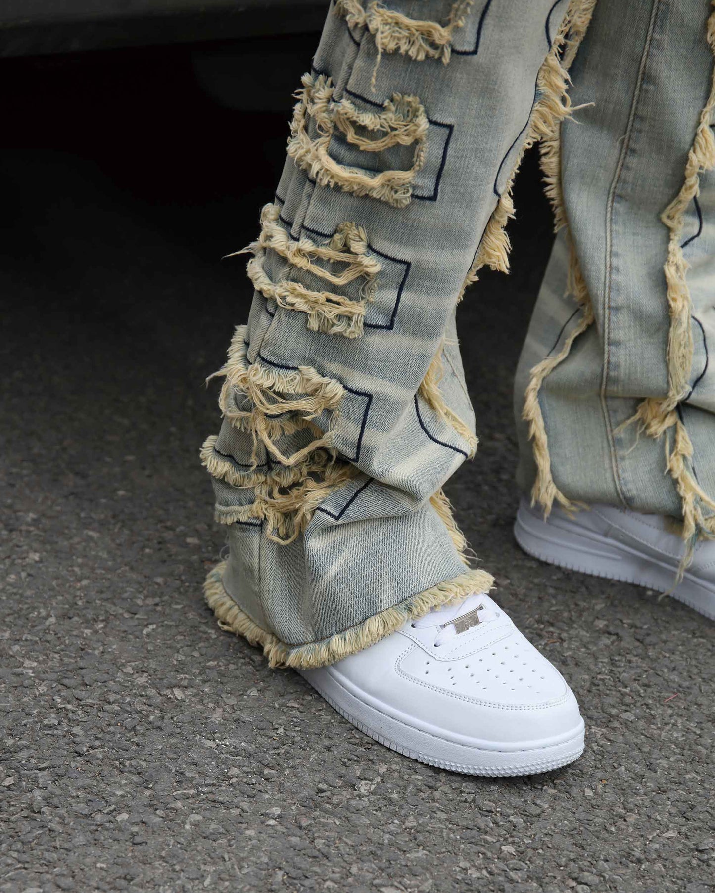 Logeqi vintage blue stacked jeans with heavy distressed details and frayed edges paired with white sneakers