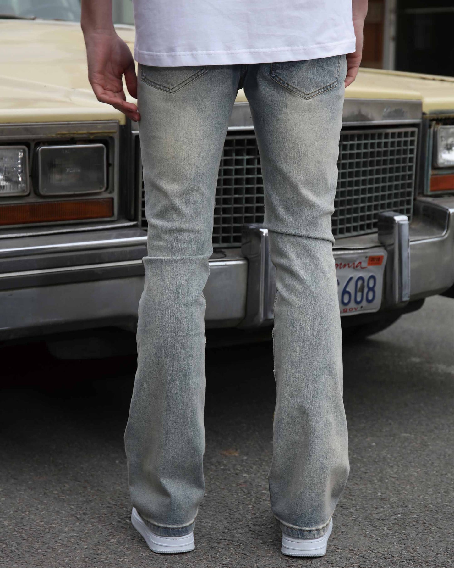 Logeqi vintage distressed blue jeans shown from the back worn by a person standing in front of a classic car
