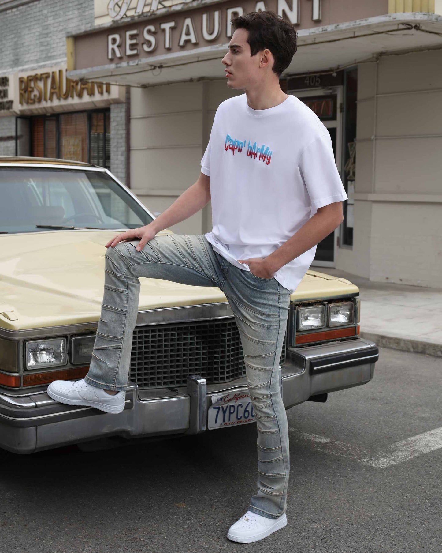 Man wearing Logeqi vintage distressed blue jeans paired with white sneakers and a graphic tee