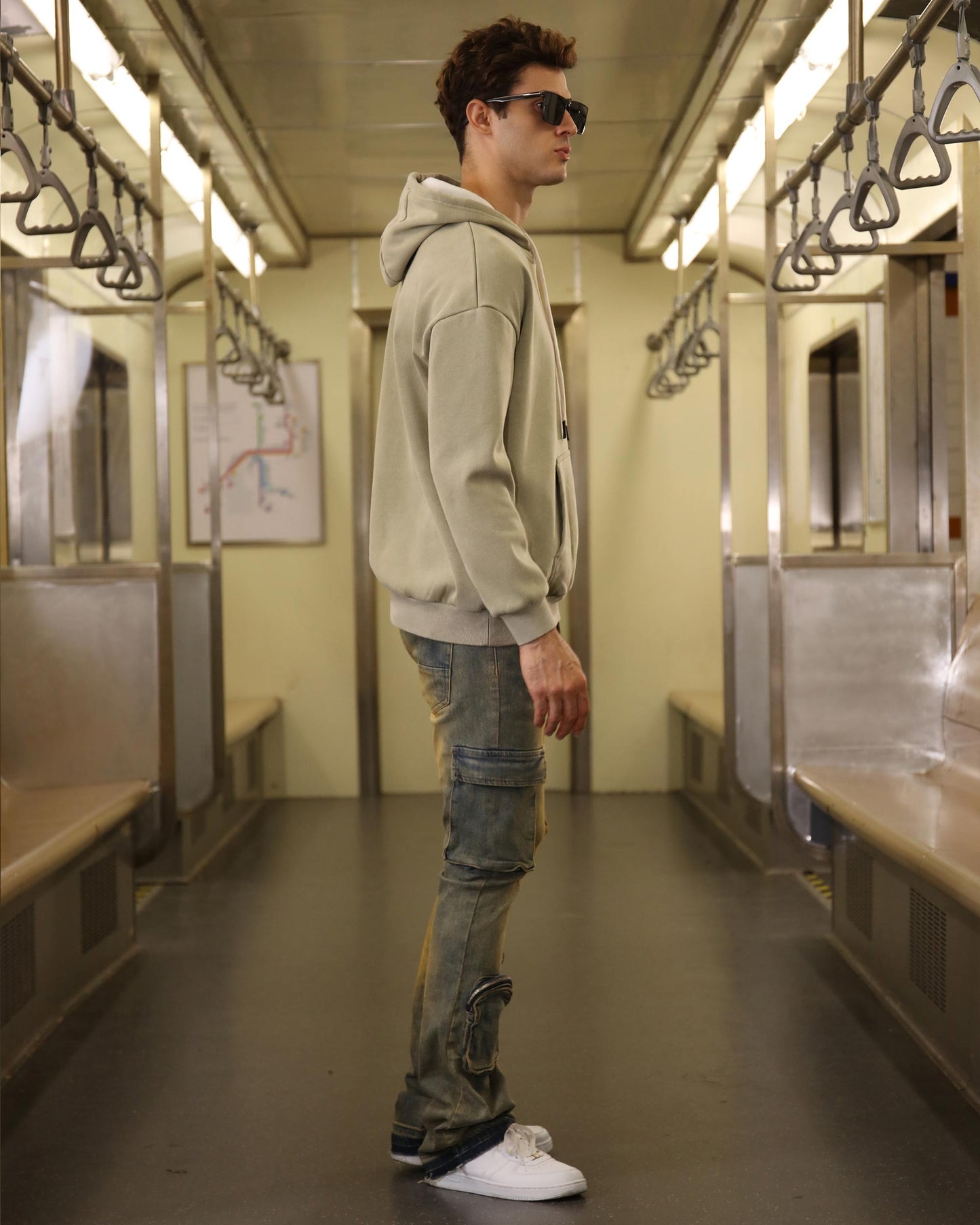 Man wearing vintage distressed cargo jeans with a hoodie in a subway train interior