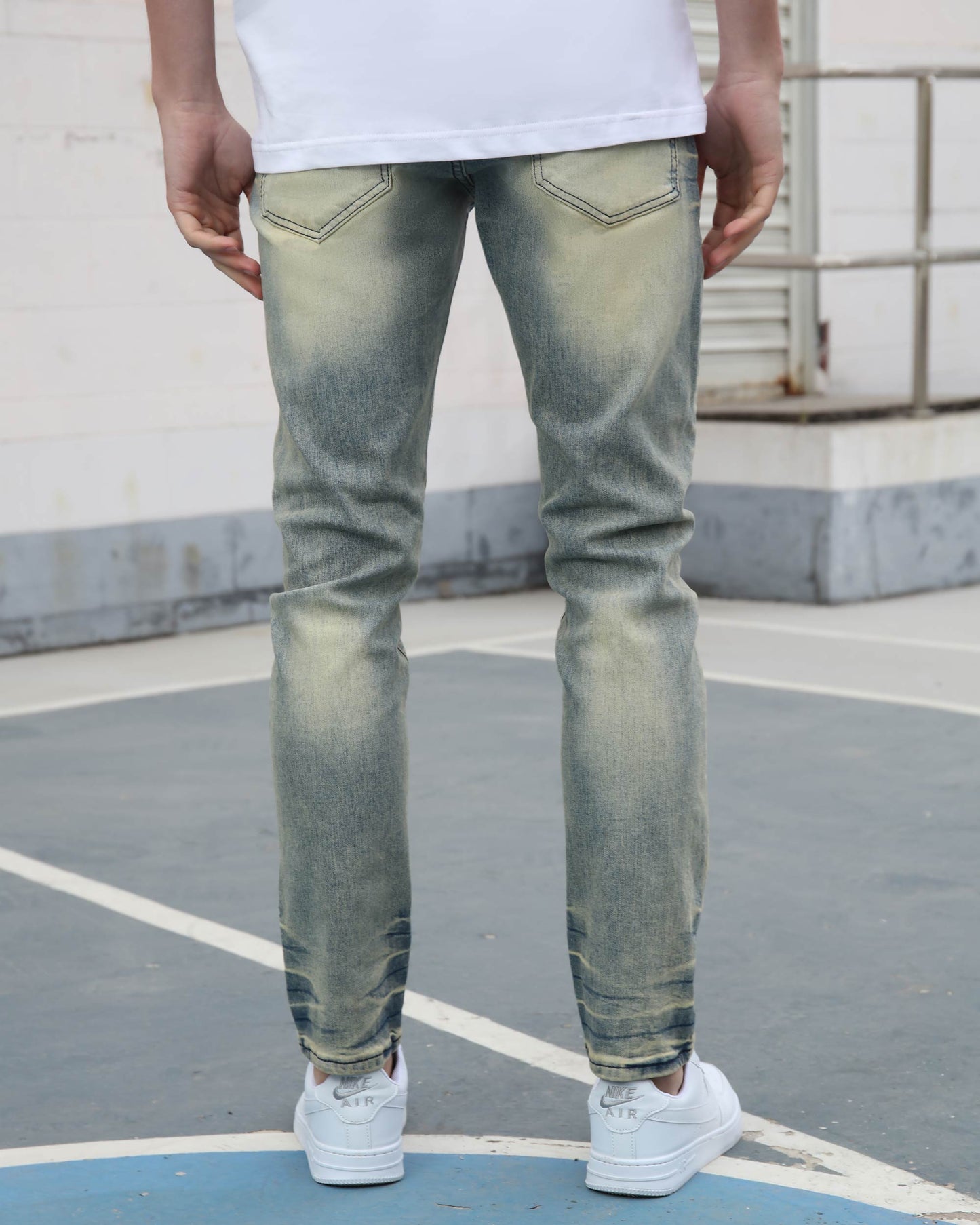 Logeqi vintage graffiti jeans in faded blue wash worn by a man standing outdoors