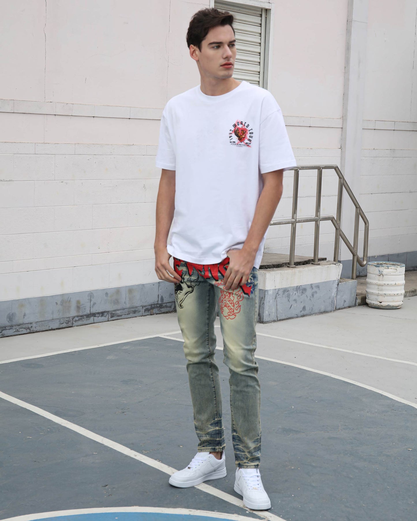 Man wearing Logeqi vintage graffiti jeans with faded washes and red graffiti designs paired with white sneakers