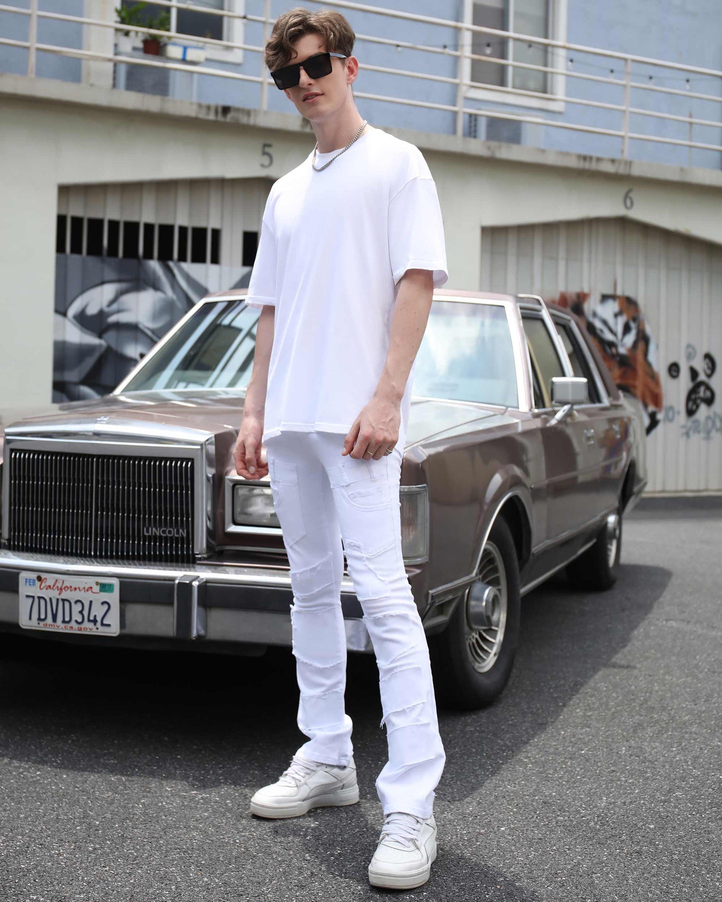 Logeqi vintage white flared jeans styled with a casual white t-shirt and sneakers by a vintage car