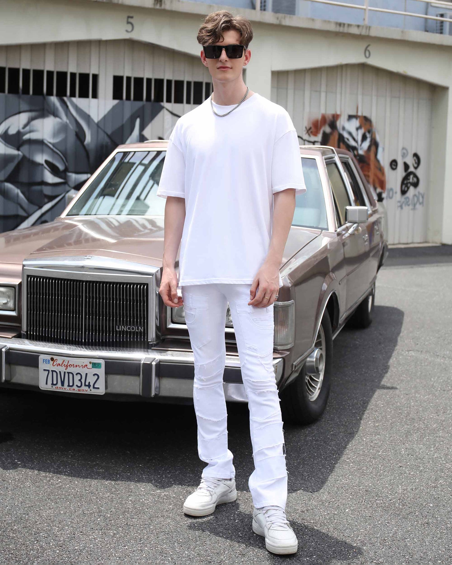 Stylish model wearing vintage white flared jeans paired with a white t-shirt and sneakers