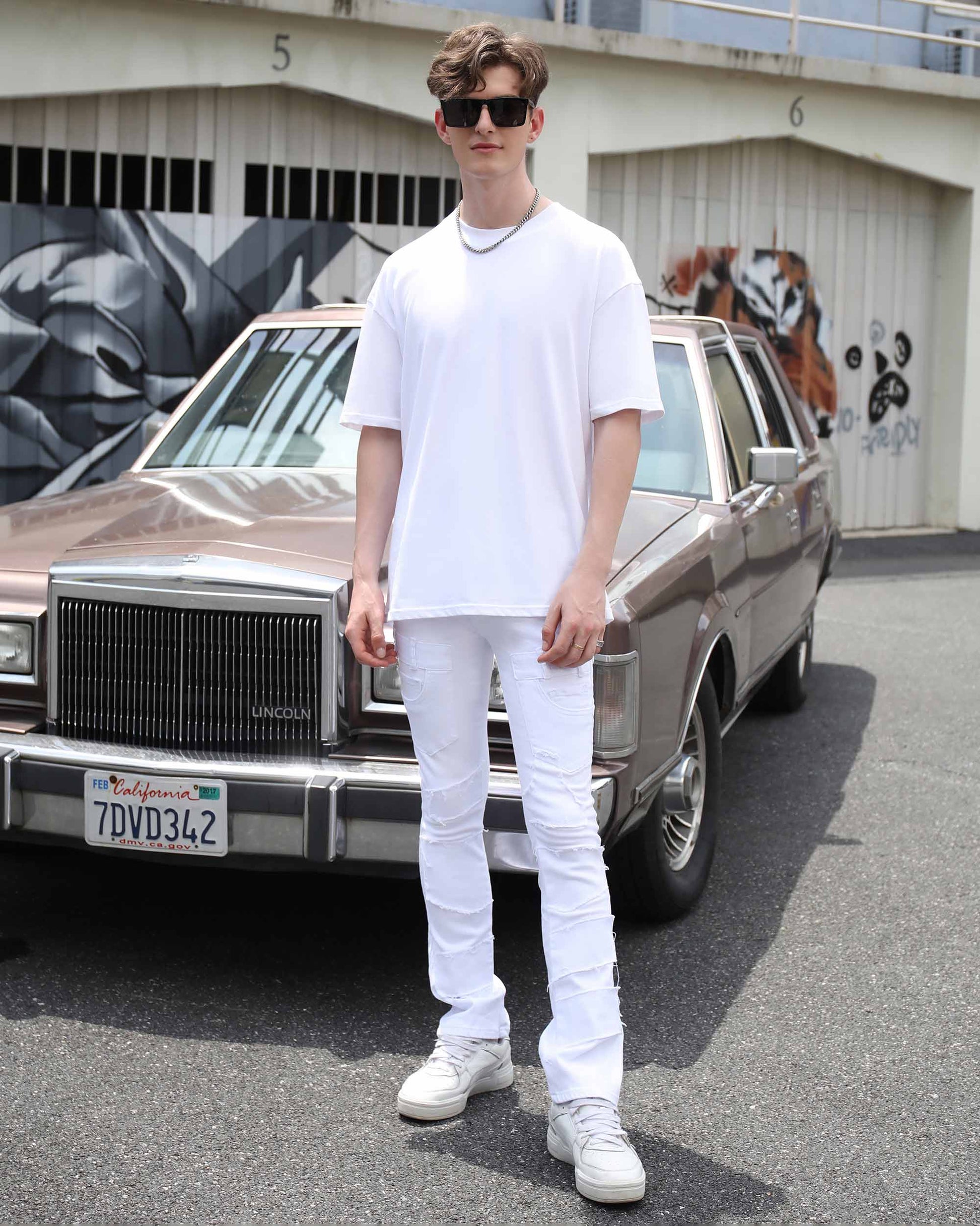 Stylish model wearing vintage white flared jeans paired with a white t-shirt and sneakers