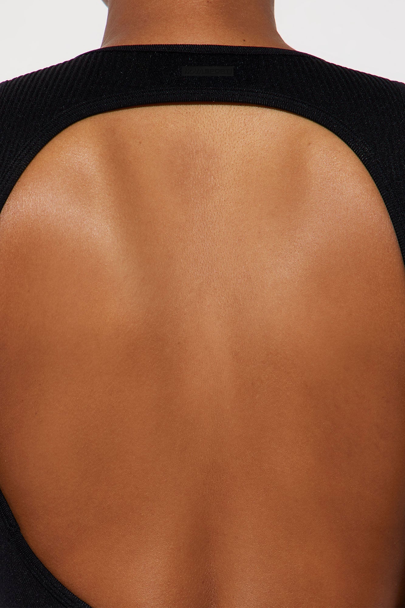 Back view of a black seamless jumpsuit for women featuring a stylish open back design