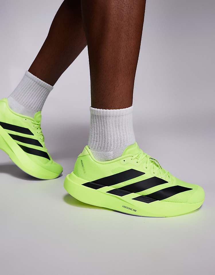 Bright green adidas Adizero Evo SL sneakers with black stripes worn with white socks