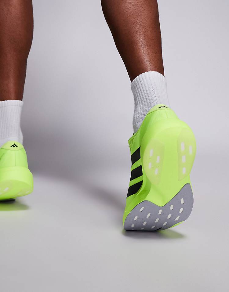 Close-up rear view of a person wearing neon green adidas Adizero Evo SL sneakers with black stripes and white socks