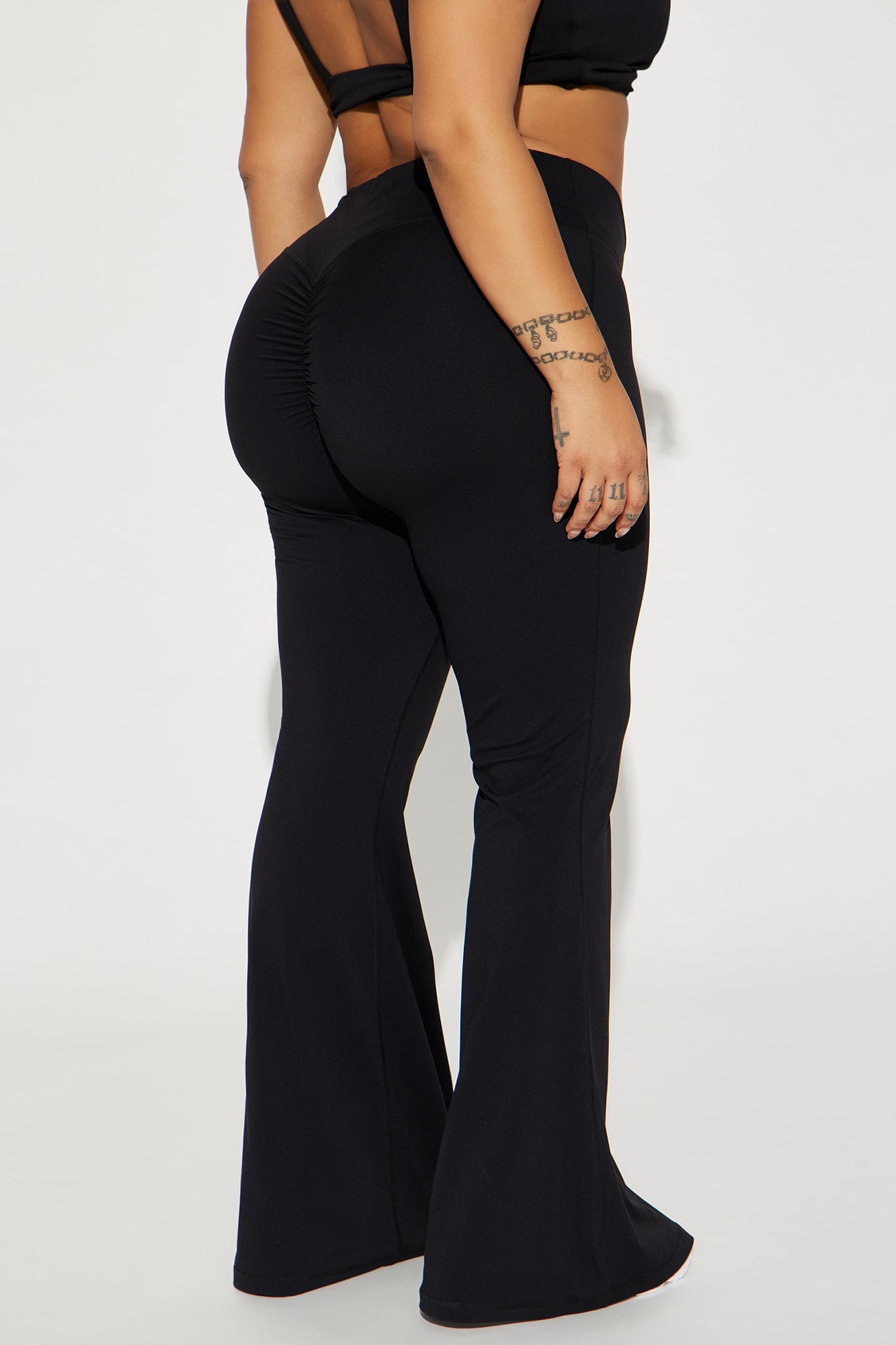 Back view of black active yoga pants by Fashion Nova with flattering fit and flare design