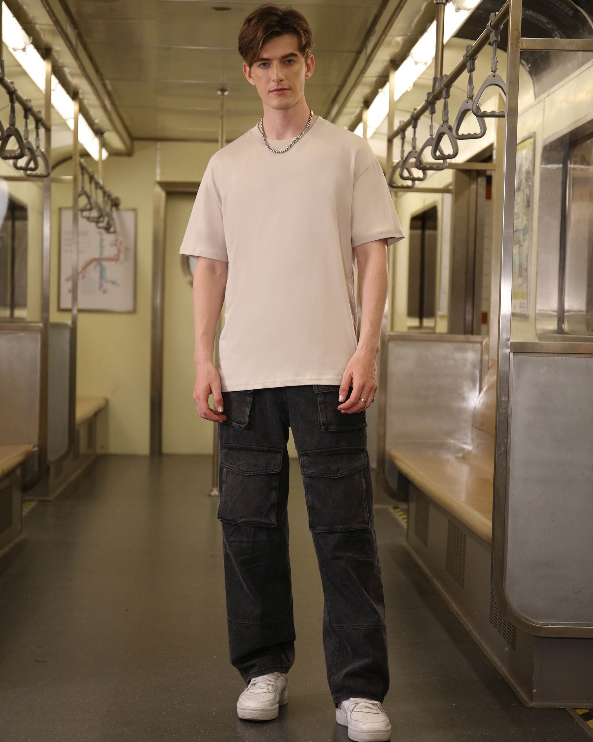 Logeqi black baggy jeans with pockets worn by male model in subway setting with casual beige t-shirt