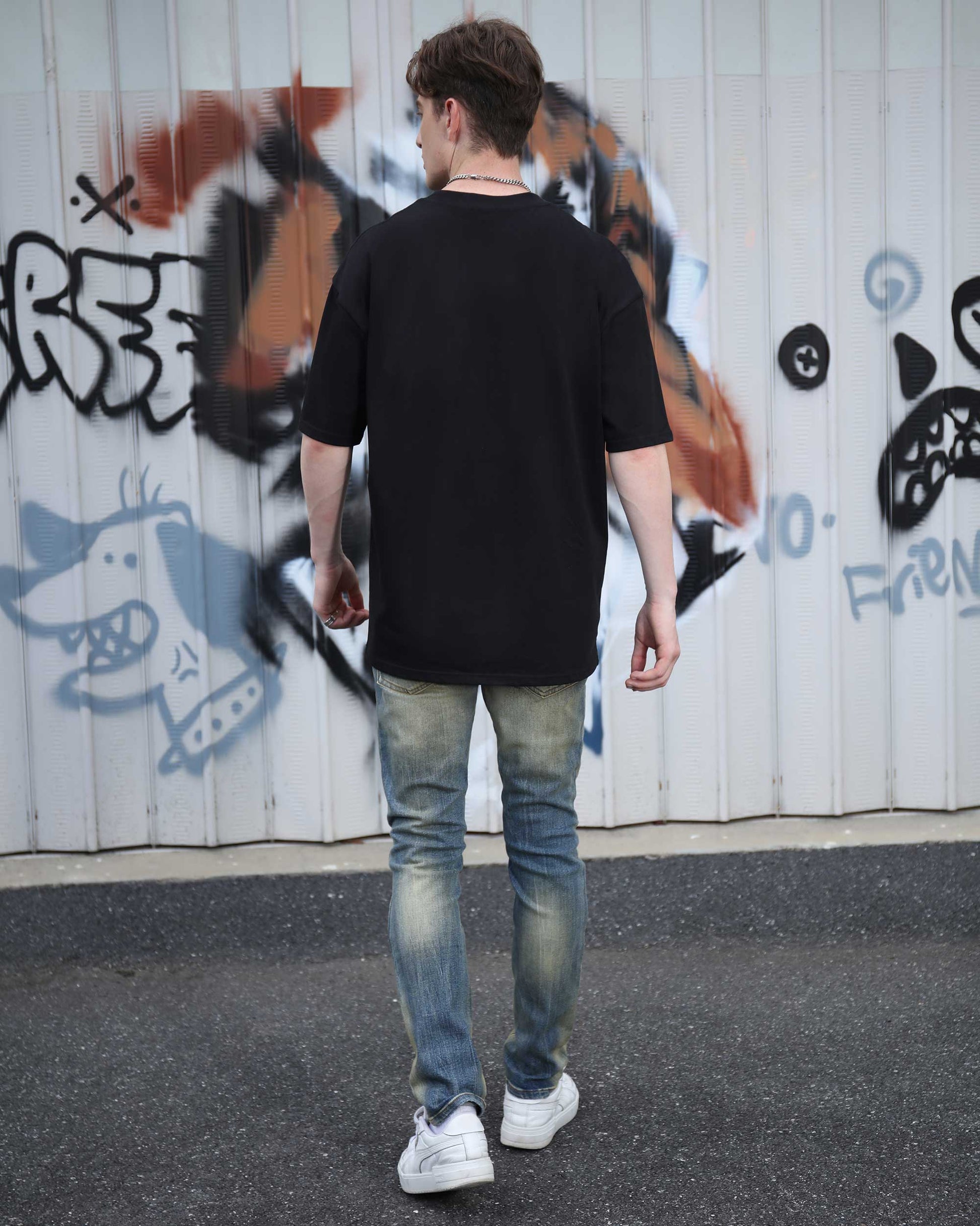 Men's Oversize Black Cotton T-Shirt in Casual Style with Back View Against Graffiti Background