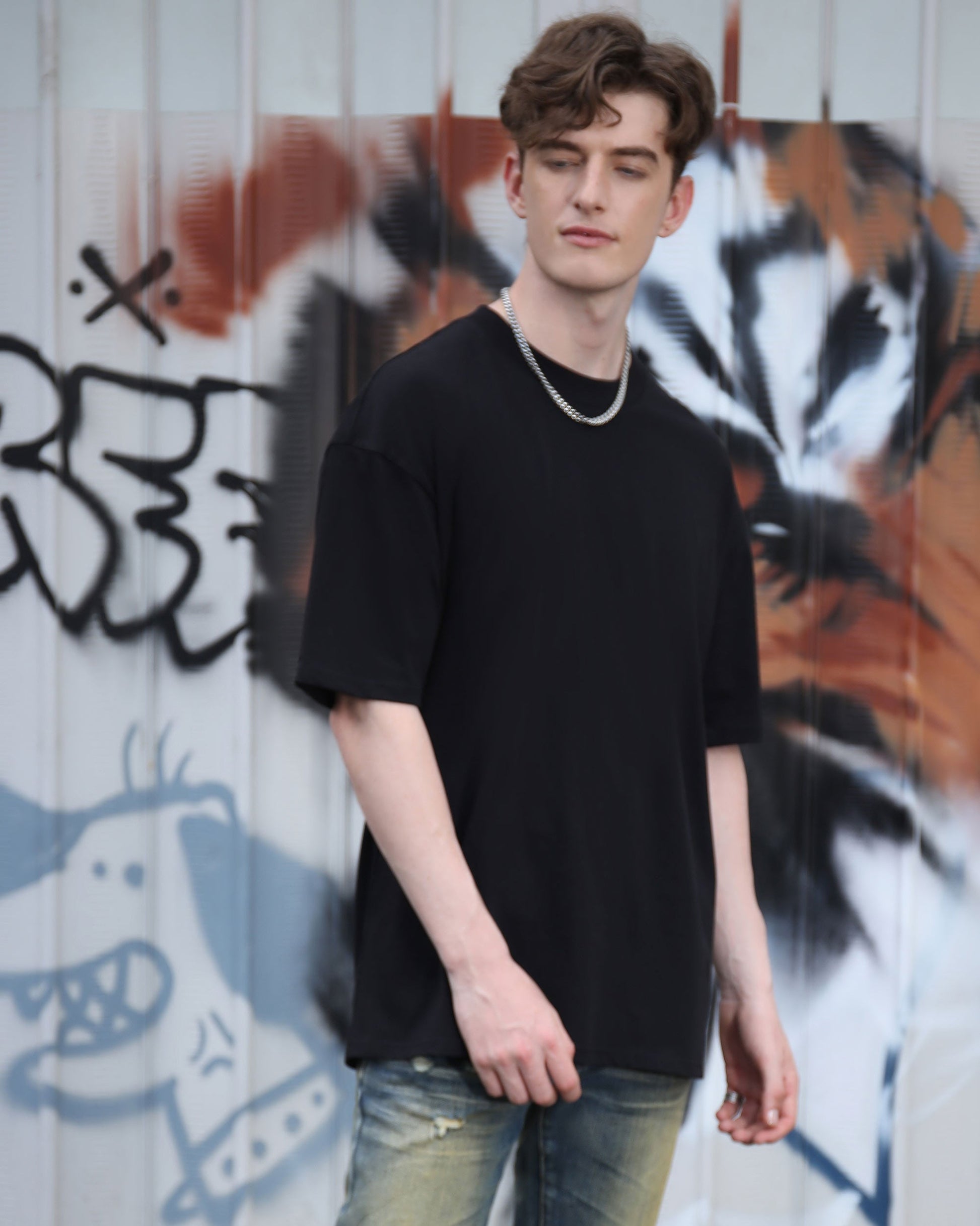 Logeqi black cotton t-shirt displayed on a model against graffiti background