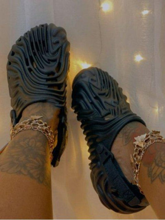 Wholesale7 black embossed hollow-out slippers worn with gold chain anklets and tattooed legs