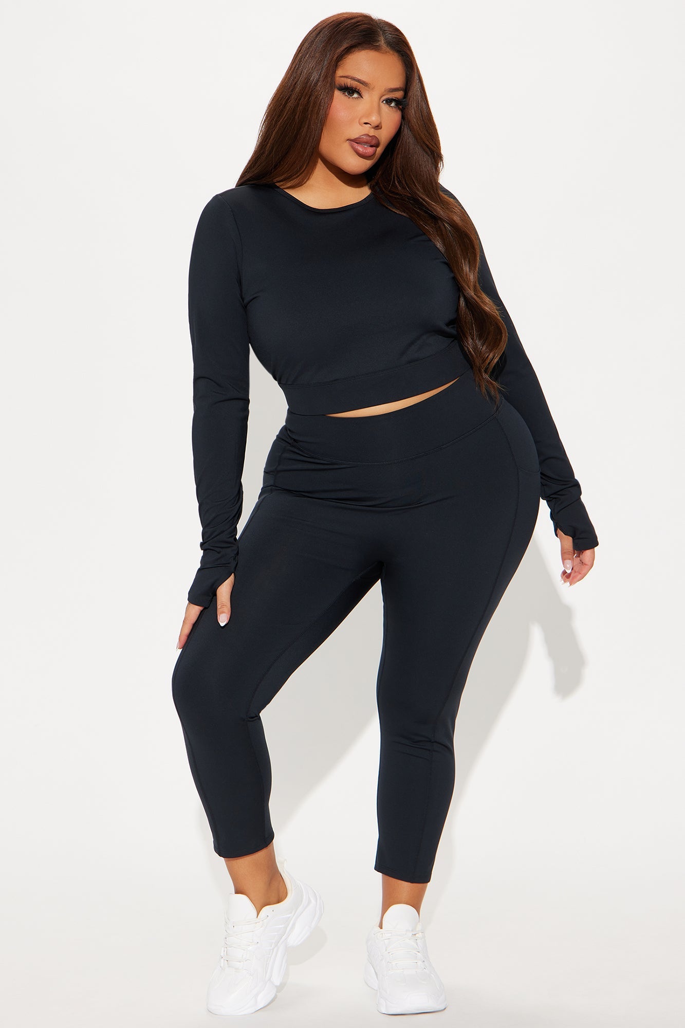 Woman wearing a black open back active top with matching leggings from Fashion Nova