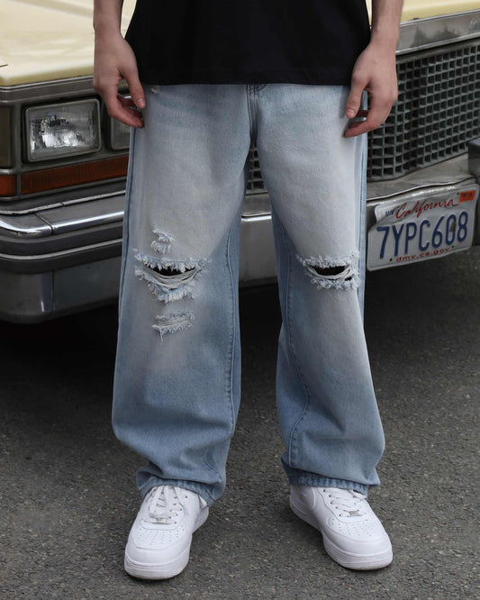 Logeqi blue ripped baggy jeans with distressed holes worn with white sneakers in casual street style