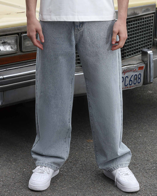 Logeqi loose fit blue jeans worn by model standing in front of vintage car with white sneakers