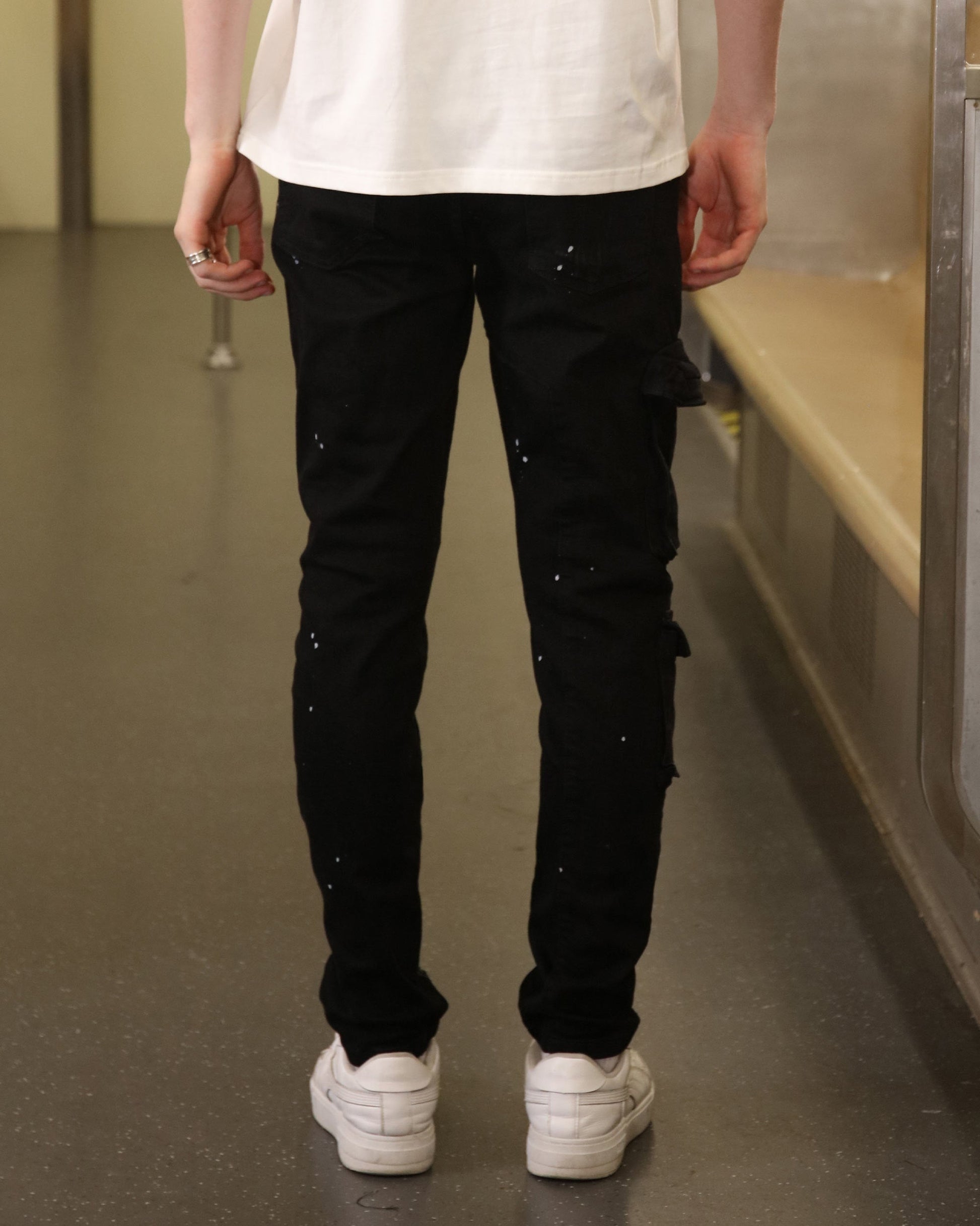 Logeqi black spray paint detail jeans worn by model showing back view with white sneakers