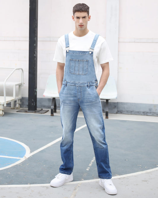 Man wearing Logeqi classic denim overalls in light blue paired with white sneakers and a white t-shirt