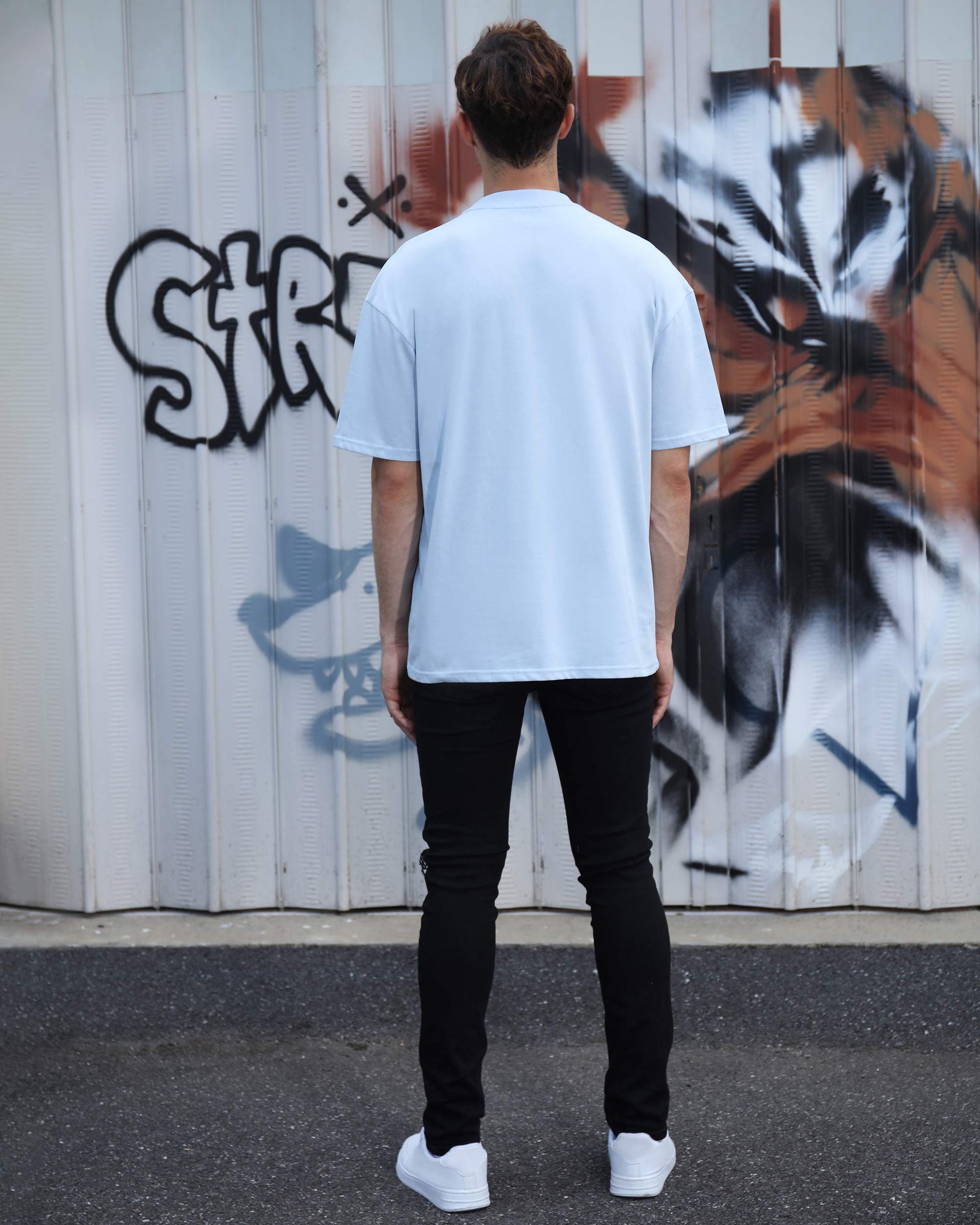 Logeqi essential solid t-shirt in light blue on model from the back, paired with black pants