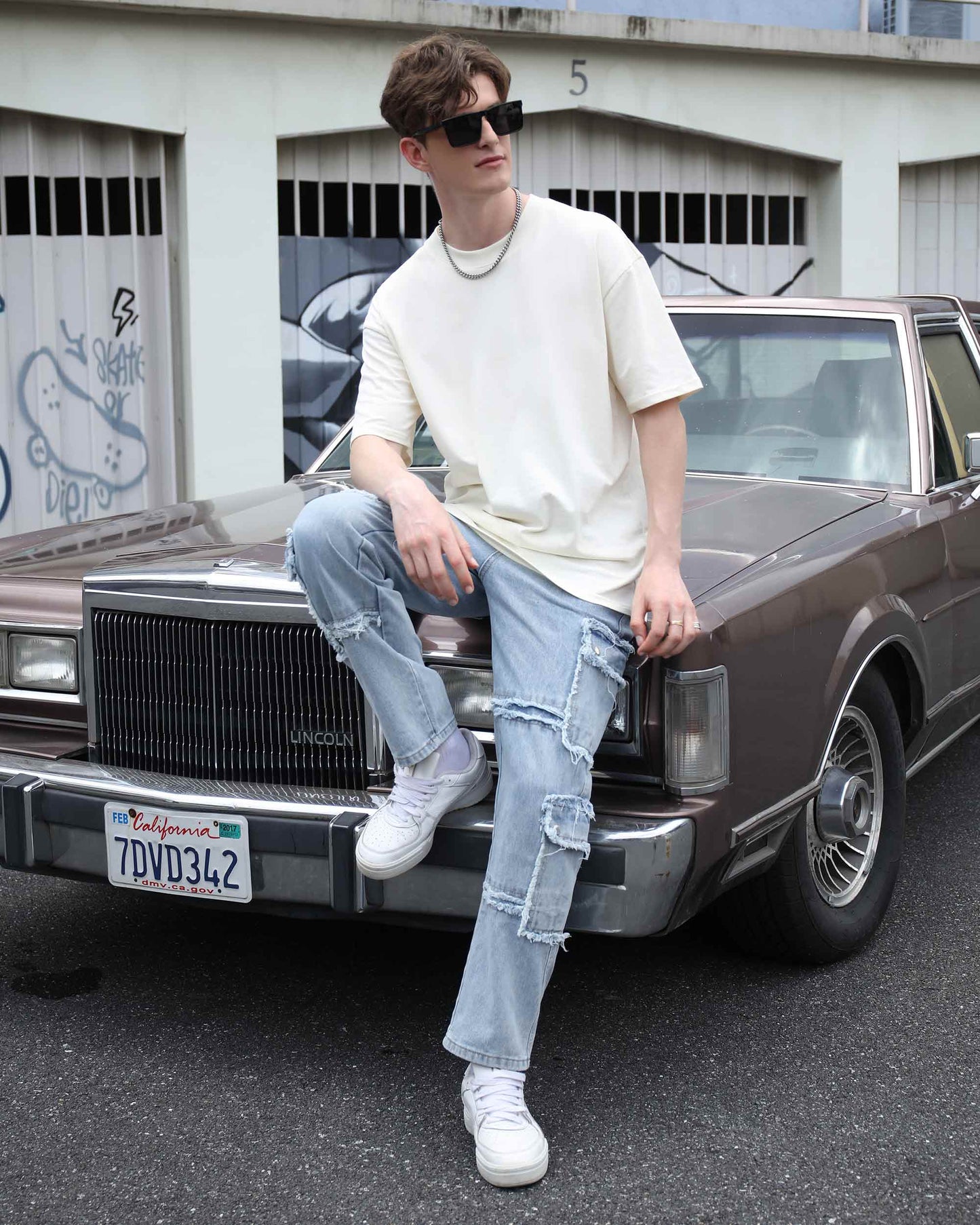 Logeqi essential solid t-shirt in cream worn by a model casually sitting on a vintage car