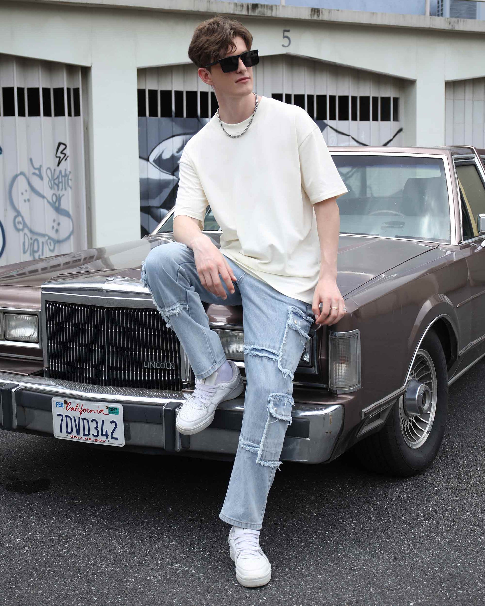 Logeqi essential solid t-shirt in cream worn by a model casually sitting on a vintage car