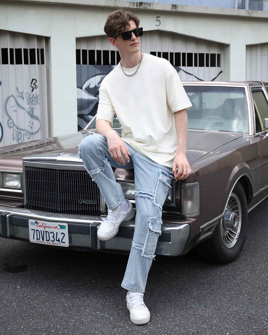 Logeqi essential solid t-shirt in cream worn by a model casually sitting on a vintage car