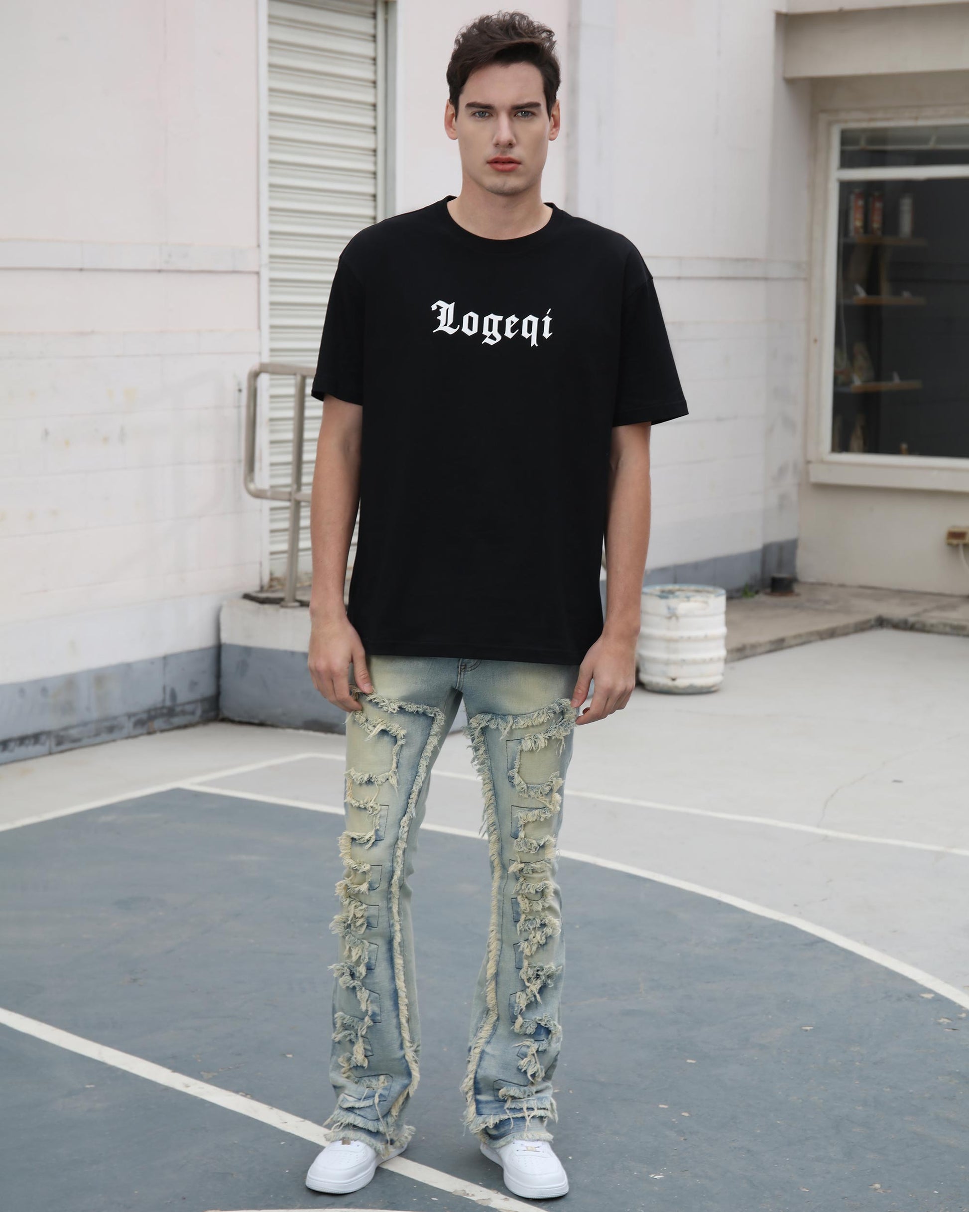 Man wearing Logeqi fringe flared jeans with distressed details and a black logo t-shirt