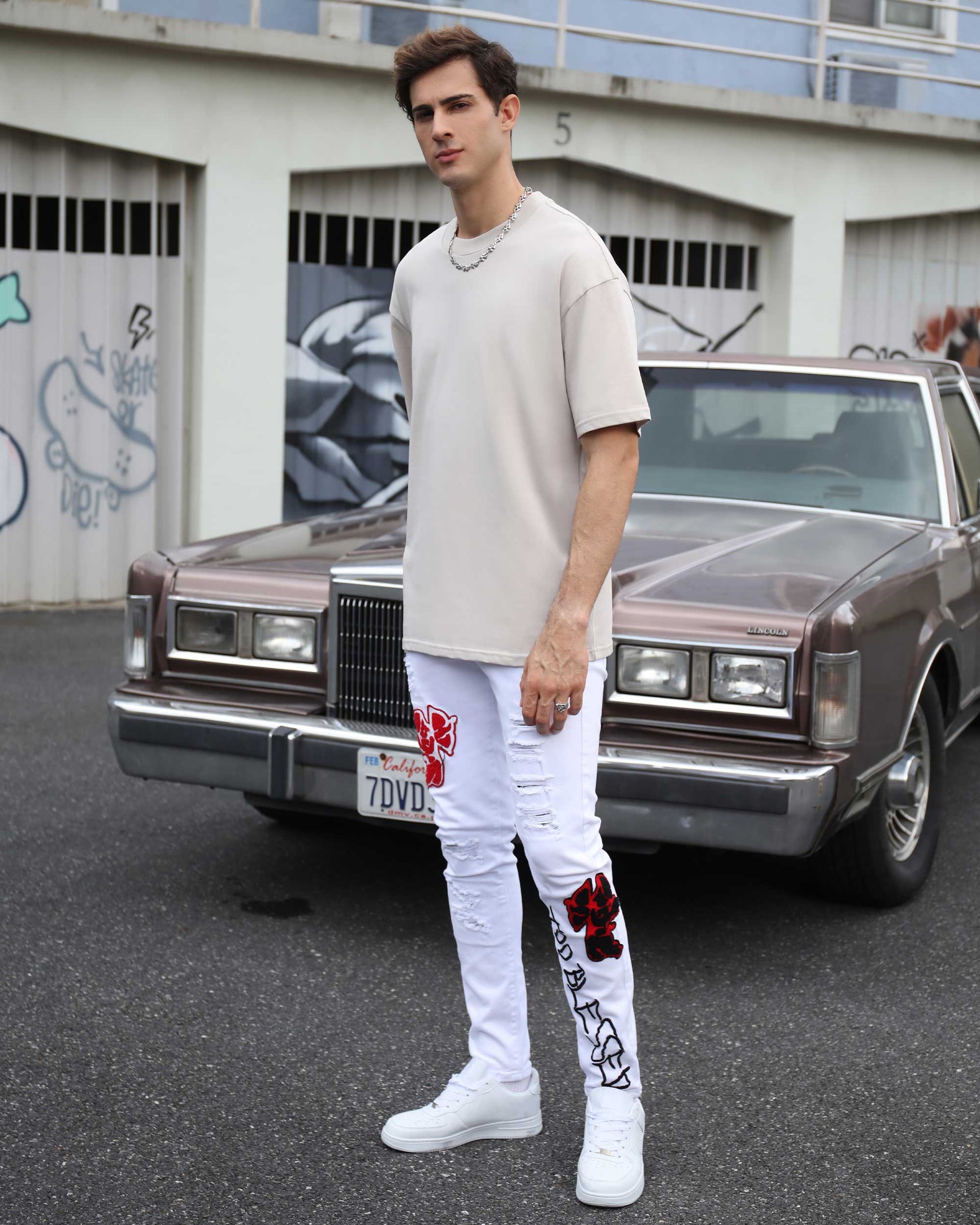 Logeqi graffiti embroidered jeans in white with vibrant red embroidery details, styled with a casual top