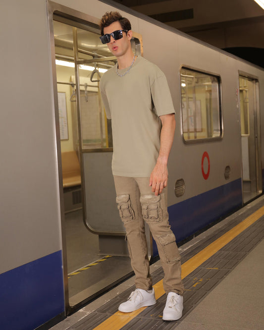 Stylish man in a green crew neck t-shirt with cargo pants and sunglasses in subway setting