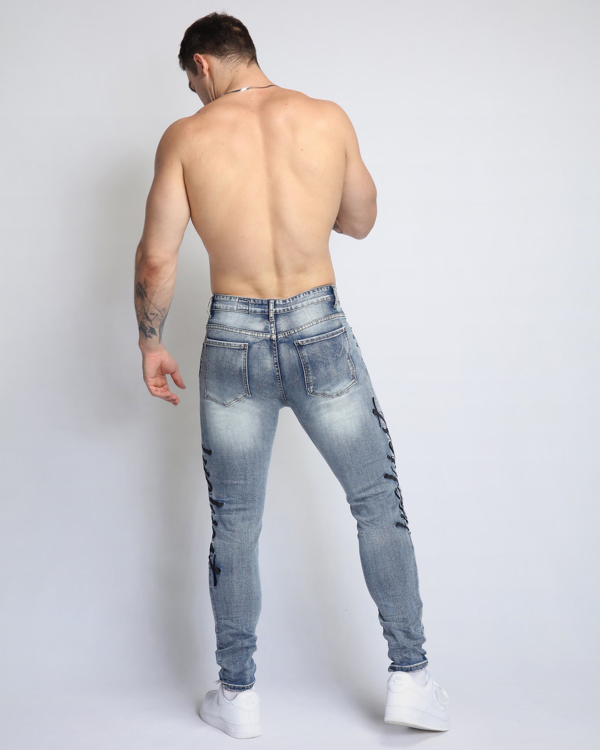 Rear view of a man wearing light wash blue ripped jeans from Logeqi for a stylish casual look