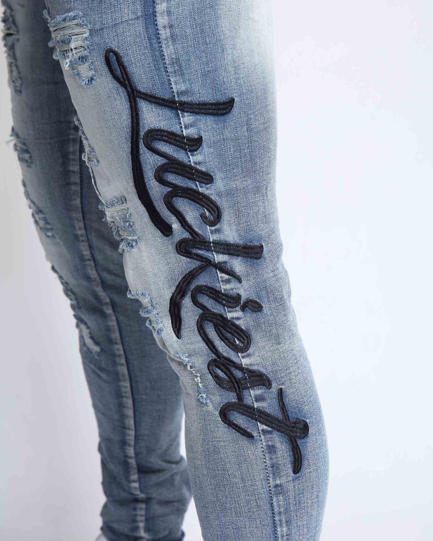 Logeqi light wash blue ripped jeans featuring stylish embroidered 'Luckiest' detail on the leg