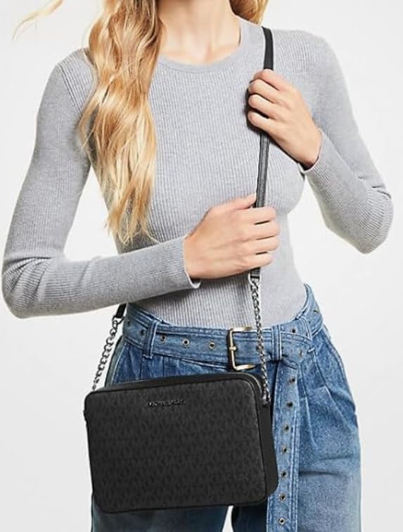 Stylish woman holding a Michael Kors vanilla crossbody bag with a sleek design and adjustable strap
