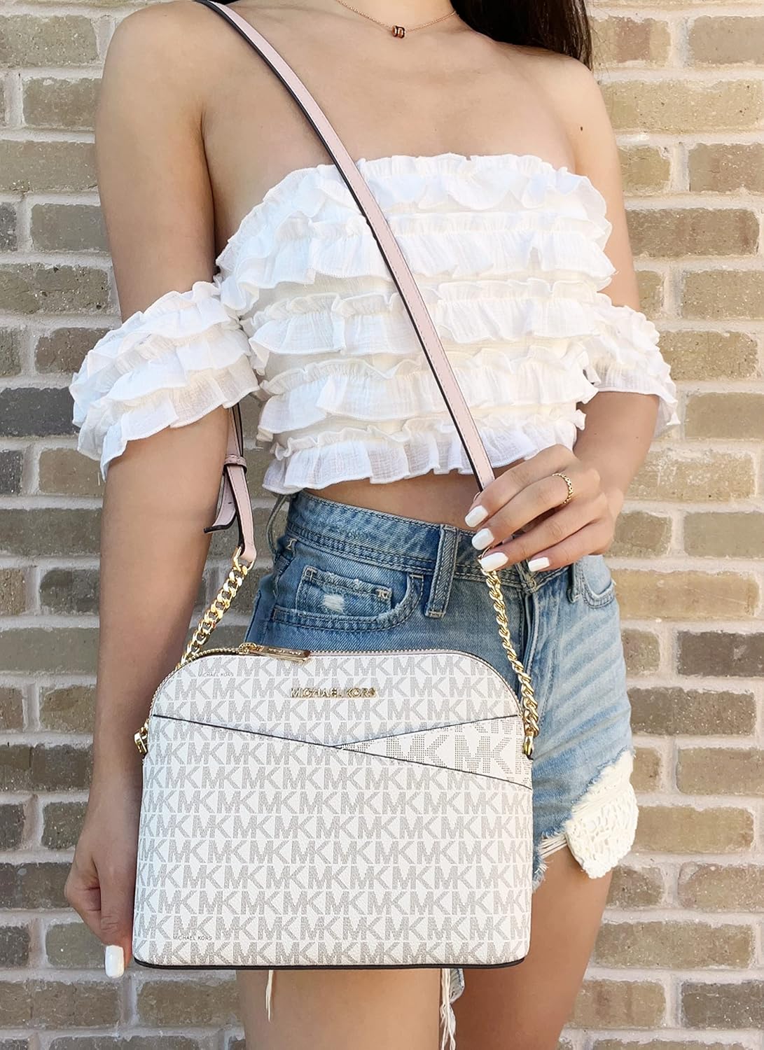 Stylish woman holding a Michael Kors crossbody leather handbag with a chic design and chain strap