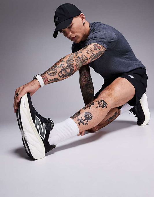 Man stretching wearing New Balance running shoes black with white soles and logo in a studio setting