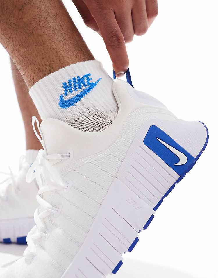 Close-up of Nike Free Metcon 6 white blue sneakers with a hand adjusting the heel tab
