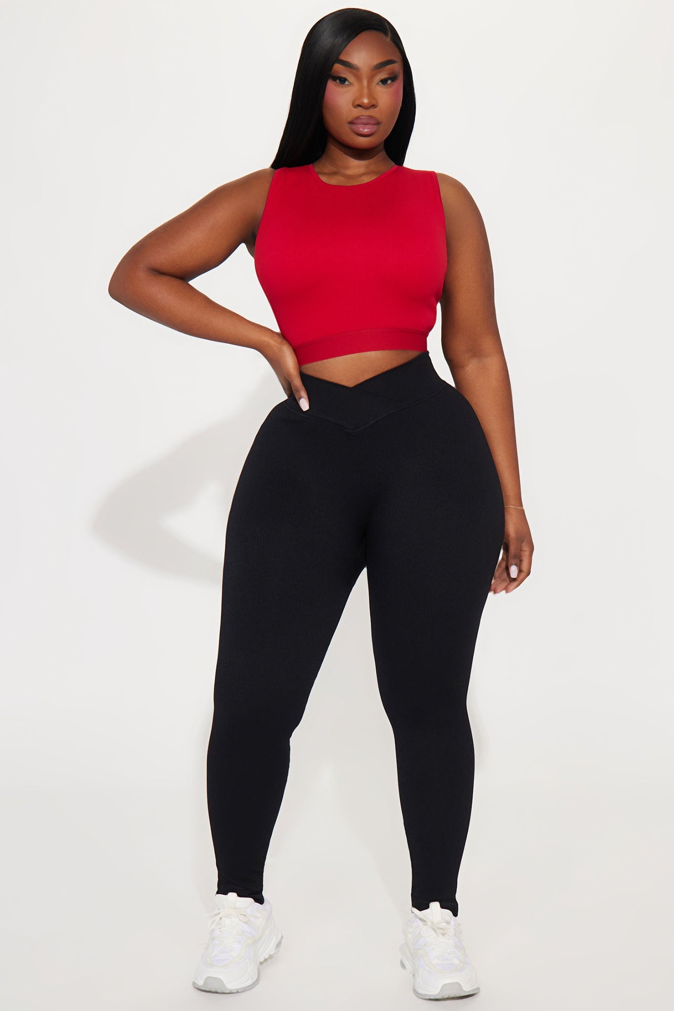 Model wearing black seamless active leggings paired with a red cropped tank top for a stylish workout look