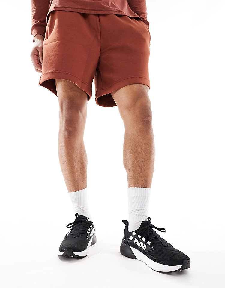 Man wearing PUMA Retaliate 3 black sneakers with brown shorts and white socks